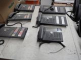 several telephones are lined up on a table in a room