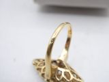 a gold ring on a white surface with a box in the background