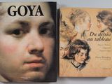 deux livres posés sur une table, à côté d'un tableau représentant le visage d'une femme et d'un portrait représentant le visage d'un homme
