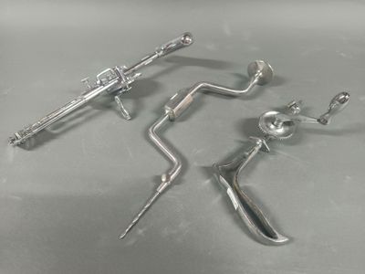 three metal tools are sitting on a table with a white background