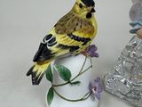 two figurines of birds sitting on top of a vase