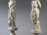 deux statues représentant un homme et une femme, posées sur des socles