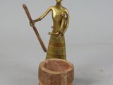 brass figurine of a woman holding a staff and a wooden bowl