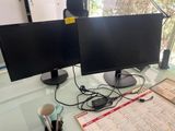 two computer monitors sitting on a desk with a cup of coffee