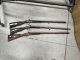 quatre armes à feu posées par terre à côté d'une paire de chaussures