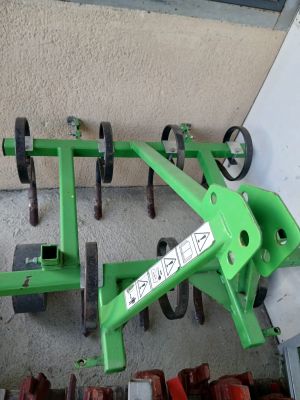 a green plow sitting on the ground next to other tools