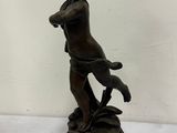 une statue antique en bronze représentant un garçon avec un chien, posée sur un socle