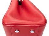 the red purse is sitting on a white surface with a white background