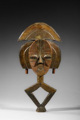 un masque en bois posé sur un socle et représentant un visage