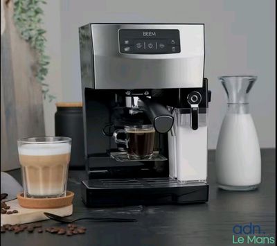 une machine à café posée sur une table, à côté d'un verre de lait