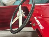 a red car with a steering wheel in a garage