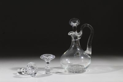 un vase en verre et deux objets en cristal posés sur une table