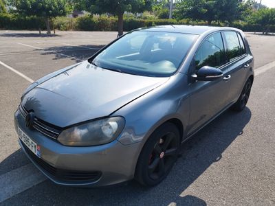 La voiture est garée sur le parking, devant les arbres.