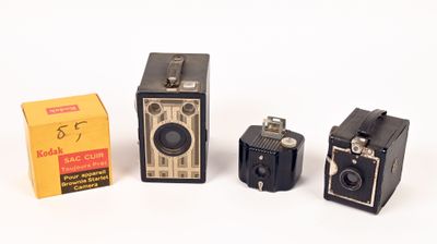 three old cameras sitting next to each other on a white surface