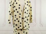 a dress and jacket on a mannequin stand in front of a wall