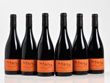 six bottles of wine are lined up in a row on a white surface