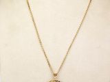 a gold necklace with a coin on a mannequin neck