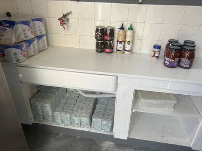 une petite cuisine avec beaucoup de bouteilles et de récipients posés sur le plan de travail