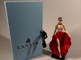 a figurine of a woman in a red dress next to a blue box