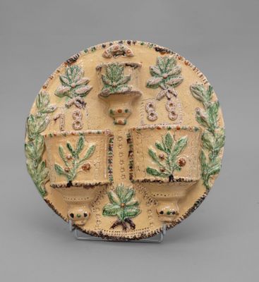 an image of a decorative plate with a cross and leaves on it