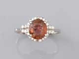 un gros plan d'une bague ornée d'une pierre orange entourée de diamants blancs