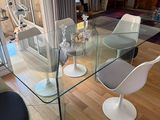 a glass dining table with four chairs in the middle of the room