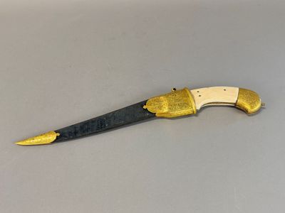 an old knife with a gold handle sitting on top of a table