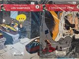 Deux bandes dessinées sont exposées sur une table devant un mur.