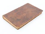 an old book with a brown cover sitting on top of a white surface