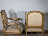 pair of antique chairs with upholstered arms and back cushions