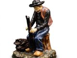 figurine of a man sitting on a tree stump with a rifle