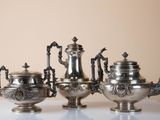 five silver teapots sitting on a white table