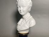 white porcelain bust of a woman with a black base and gold trim