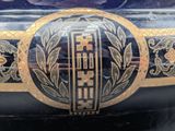 a black vase with a gold decoration on it