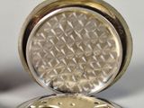 a silver pocket watch sitting on a white surface