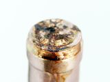 a close up of a bottle of wine with a rusted top
