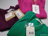 three different colored sweaters with price tags on them sitting on a table