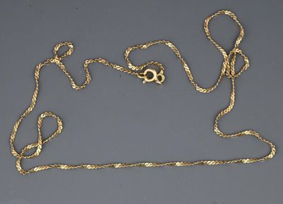a close up of a gold necklace with a chain on a gray surface