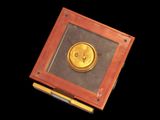 a small wooden box with a gold button on it