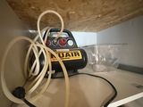 a small air compressor sitting on a shelf with a bunch of wires