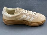 the adidas sneakers are tan and white with a light brown sole
