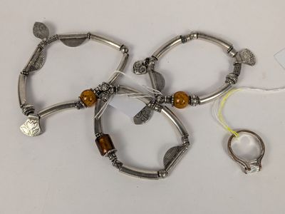 trois bracelets en argent ornés de perles en bois et une bague, posés sur un fond blanc