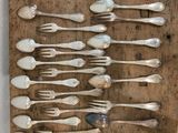 many spoons and forks laid out on a wooden board