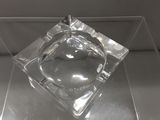 un cendrier en verre contenant une cigarette, posé sur une table