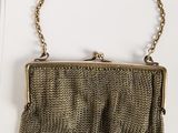 an old purse with chain hanging from it on a white surface