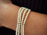 the pearl bracelet is made with three strands of white pearls and a gold clasp