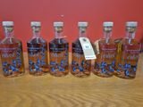 six bouteilles d'alcool sont alignées sur une table