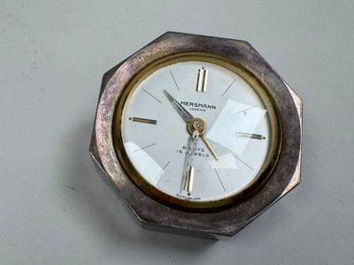 une horloge argentée et dorée posée sur un fond blanc