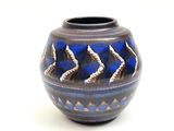 un vase bleu et noir posé sur une surface blanche