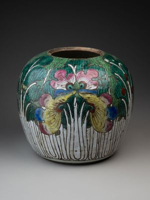 un vase avec des fleurs peintes dessus, posé sur une table